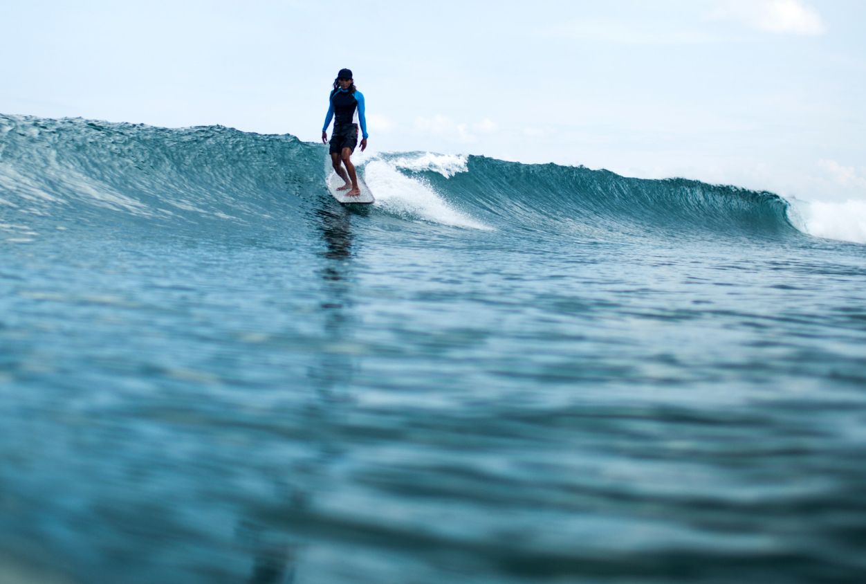 Un surfer en una ola con estilo clasico y longboard